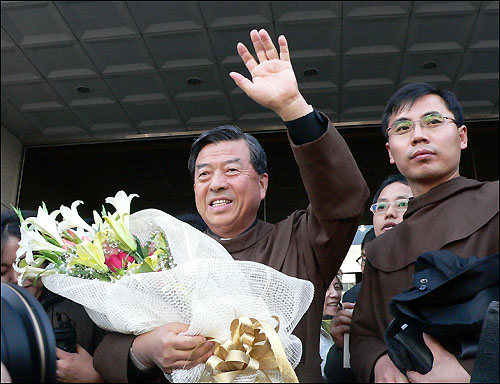 지난 2006년 11월 17일 항소심에서 무죄를 선고 받은 꽃동네 오웅진 신부가 축하의 꽃다발을 받고 지지자들에게 손을 흔들어 기쁨을 표시하고 있다.  